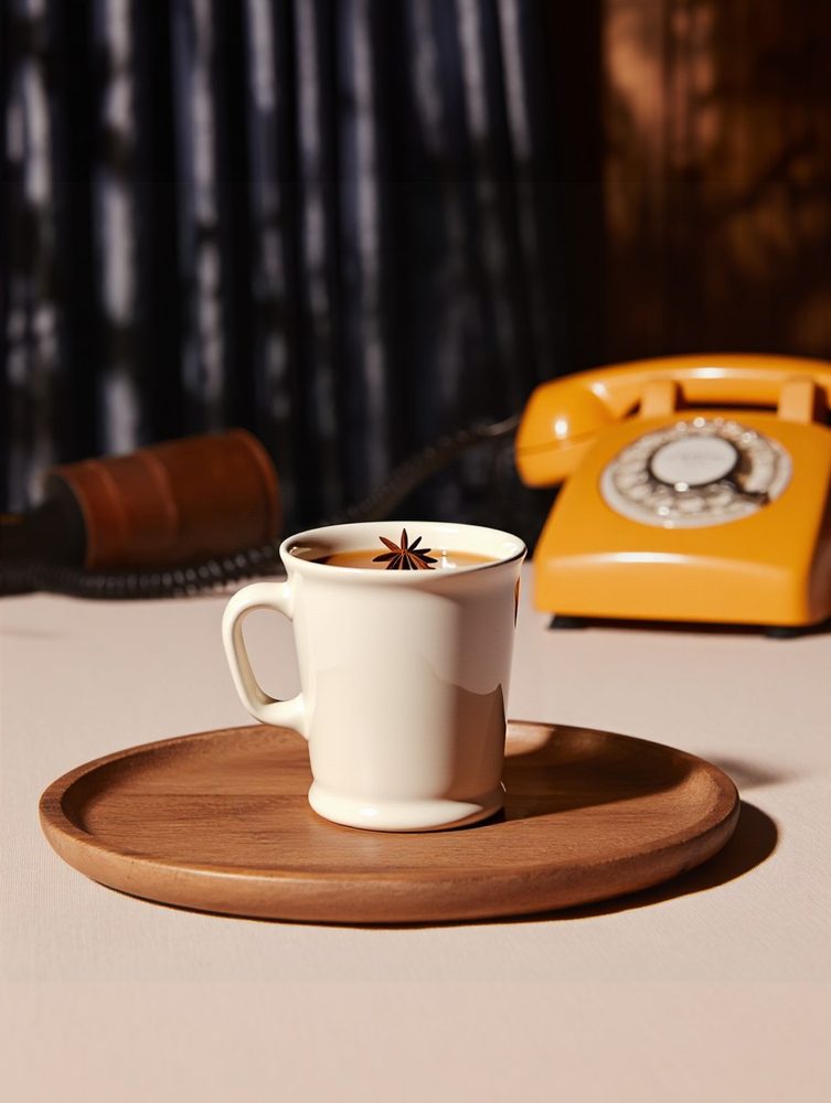 Coffee cup beside an orange rotary phone