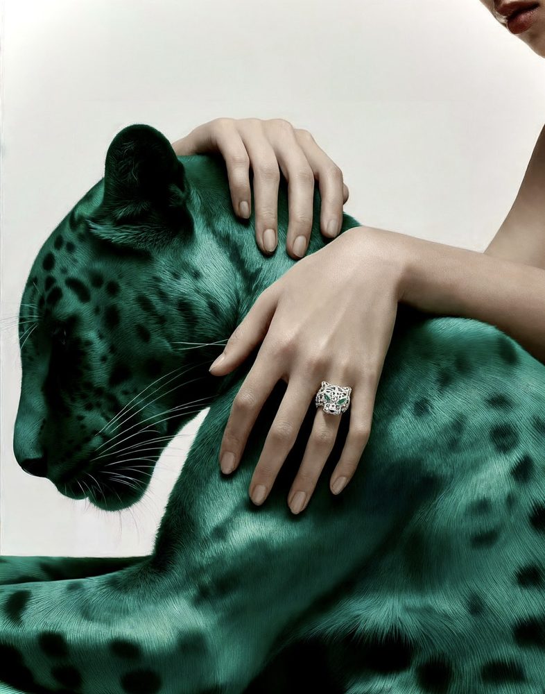 Hand with a panther ring resting on an emerald panther