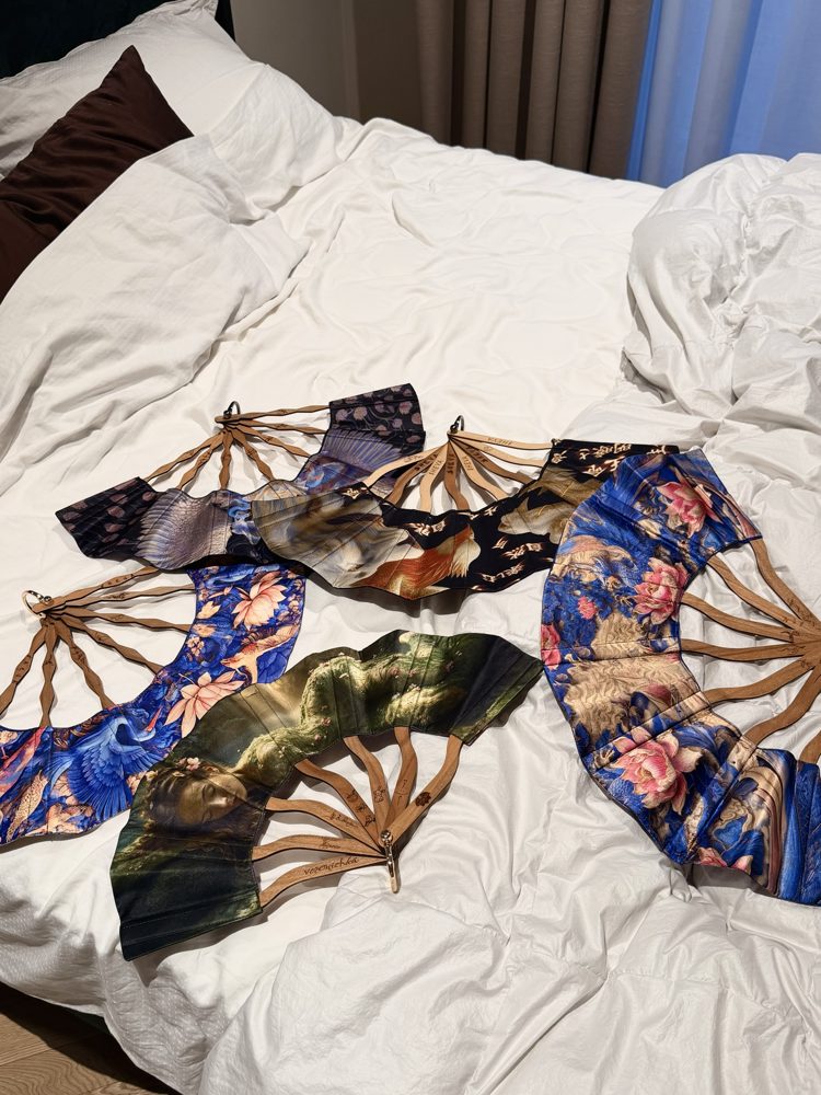 Five silk fans with engraved wooden ribs laid out on linen